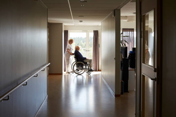 Personne âgée se déplaçant en fauteuil roulant dans une maison de retraite